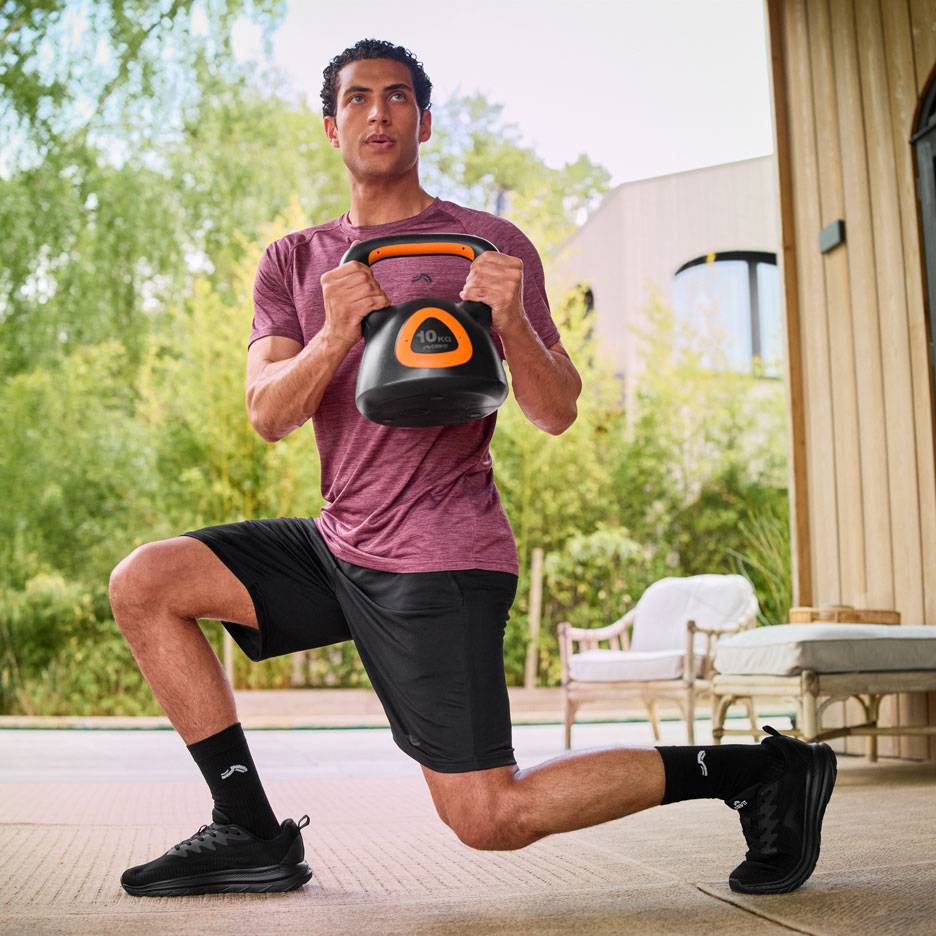 Bărbat făcând fandări cu o kettlebell de 10 kg în aer liber.