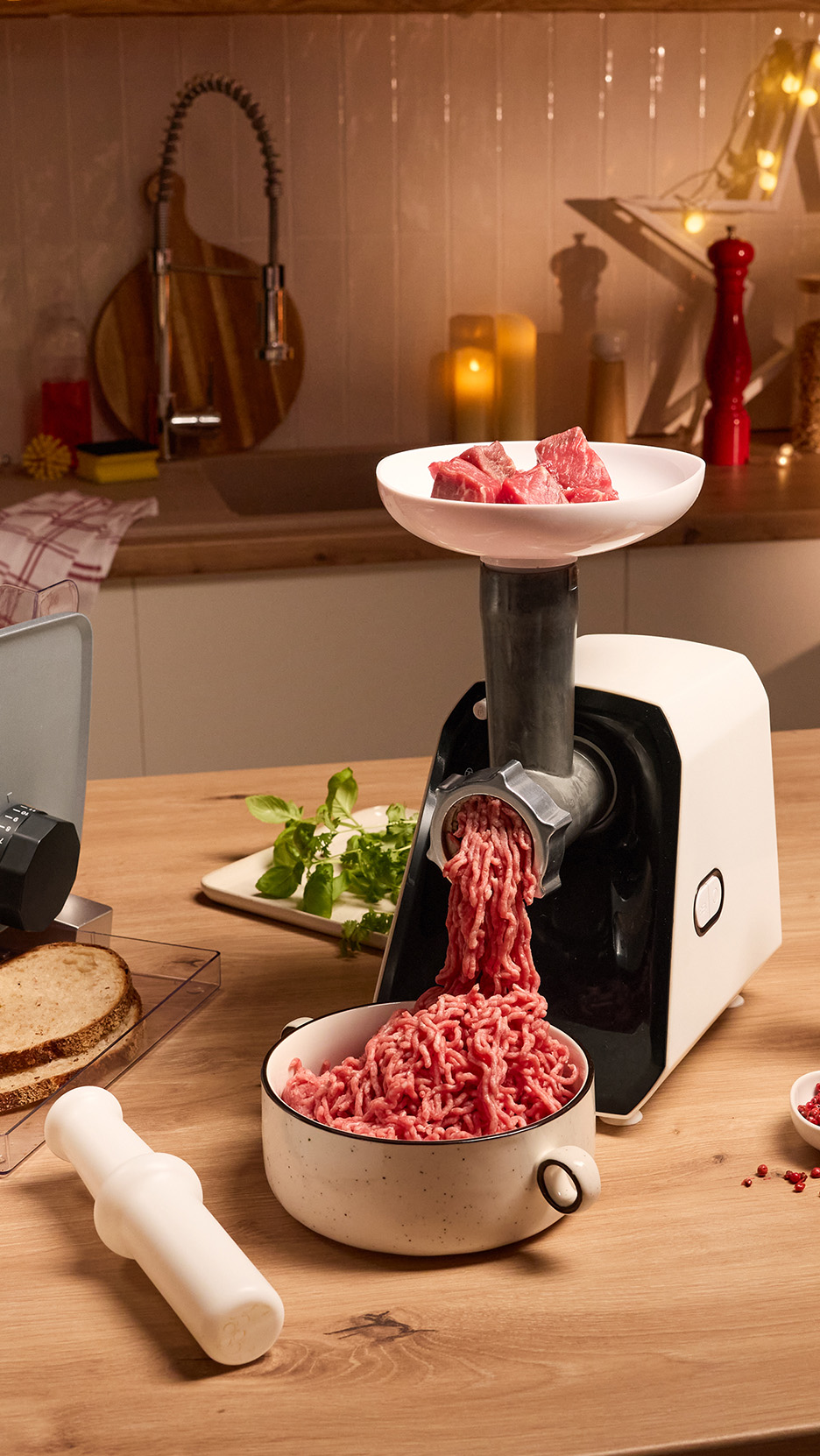 Mașină de tocat carne electrică și feliator de pâine pe o masă de bucătărie.