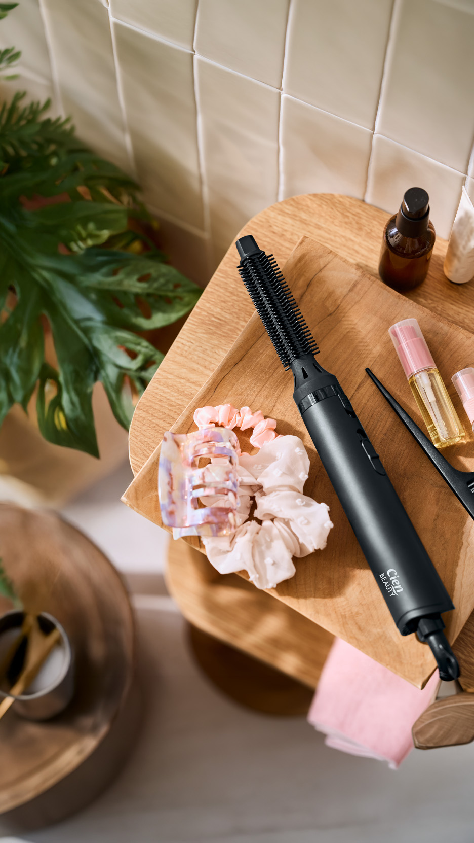 Perie electrică de păr, agrafe și elastice de păr pe o tavă de lemn, cu produse cosmetice.