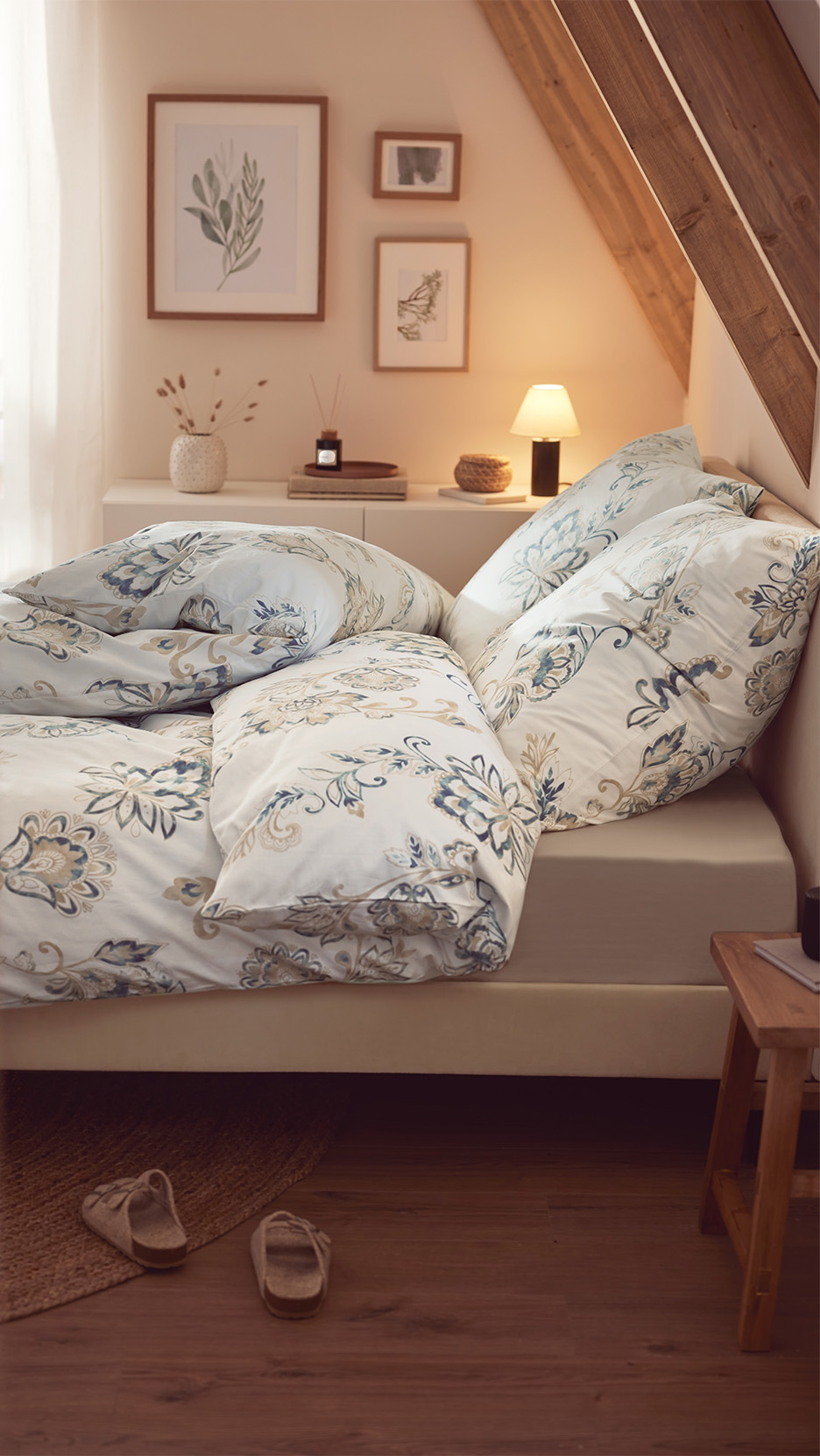 Lenjerie de pat cu model floral albastru și bej într-un dormitor mansardat, cu decor rustic.