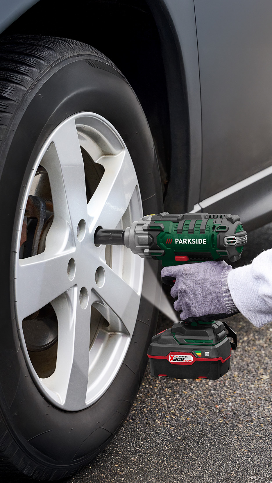 O persoană folosește o cheie de impact fără fir pentru a schimba o roată de mașină.
