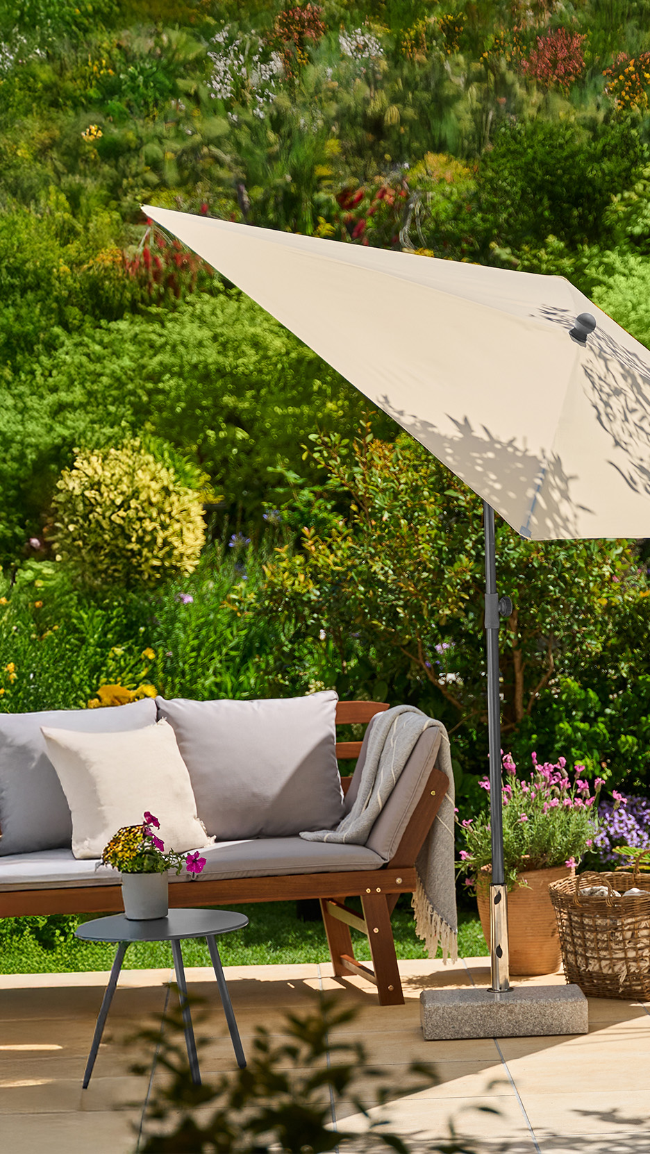 Bancă de grădină din lemn cu perne, umbrelă de soare și măsuță laterală pe o terasă.