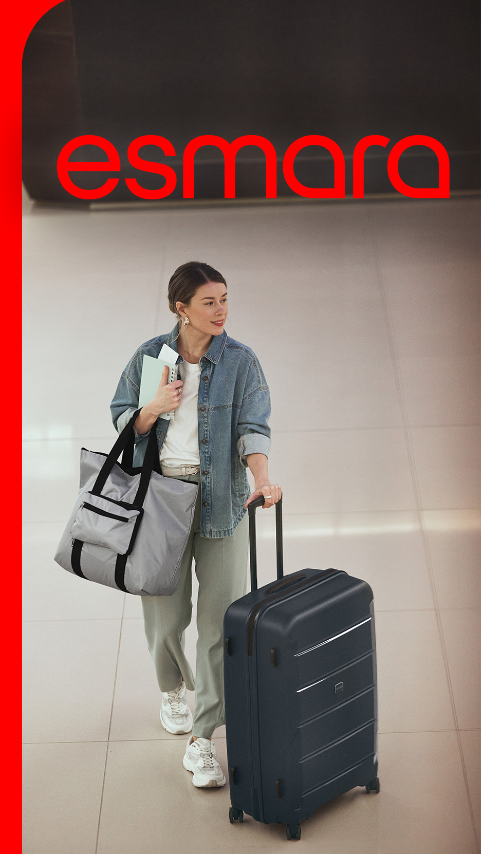 Femeie cu geantă de voiaj și troler, purtând o cămașă din denim și pantaloni, cu textul „esmra”.