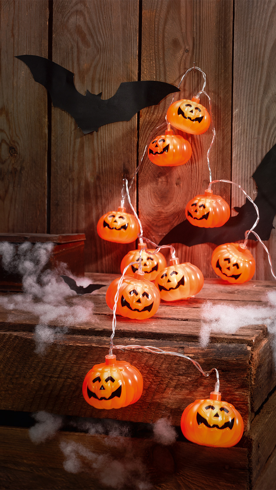 Ghirlandă luminoasă cu dovleci de Halloween, pe un fundal rustic din lemn cu lilieci.