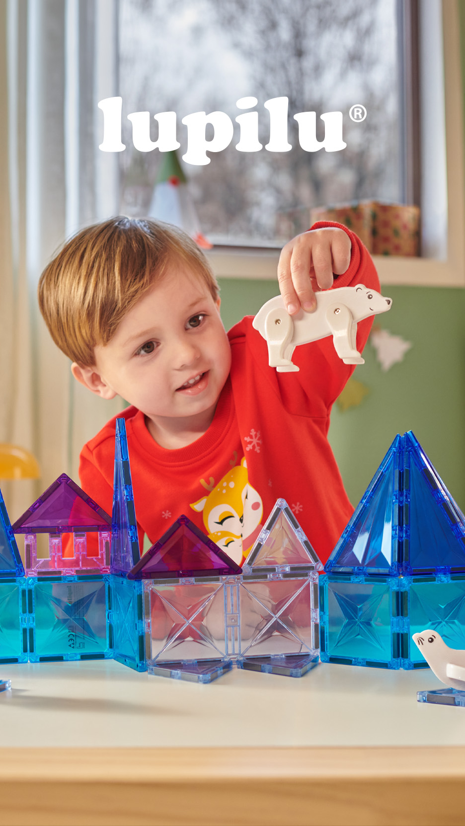 Copil care se joacă cu setul de construcție magnetic Lupilu cu piese translucide și figurine animale