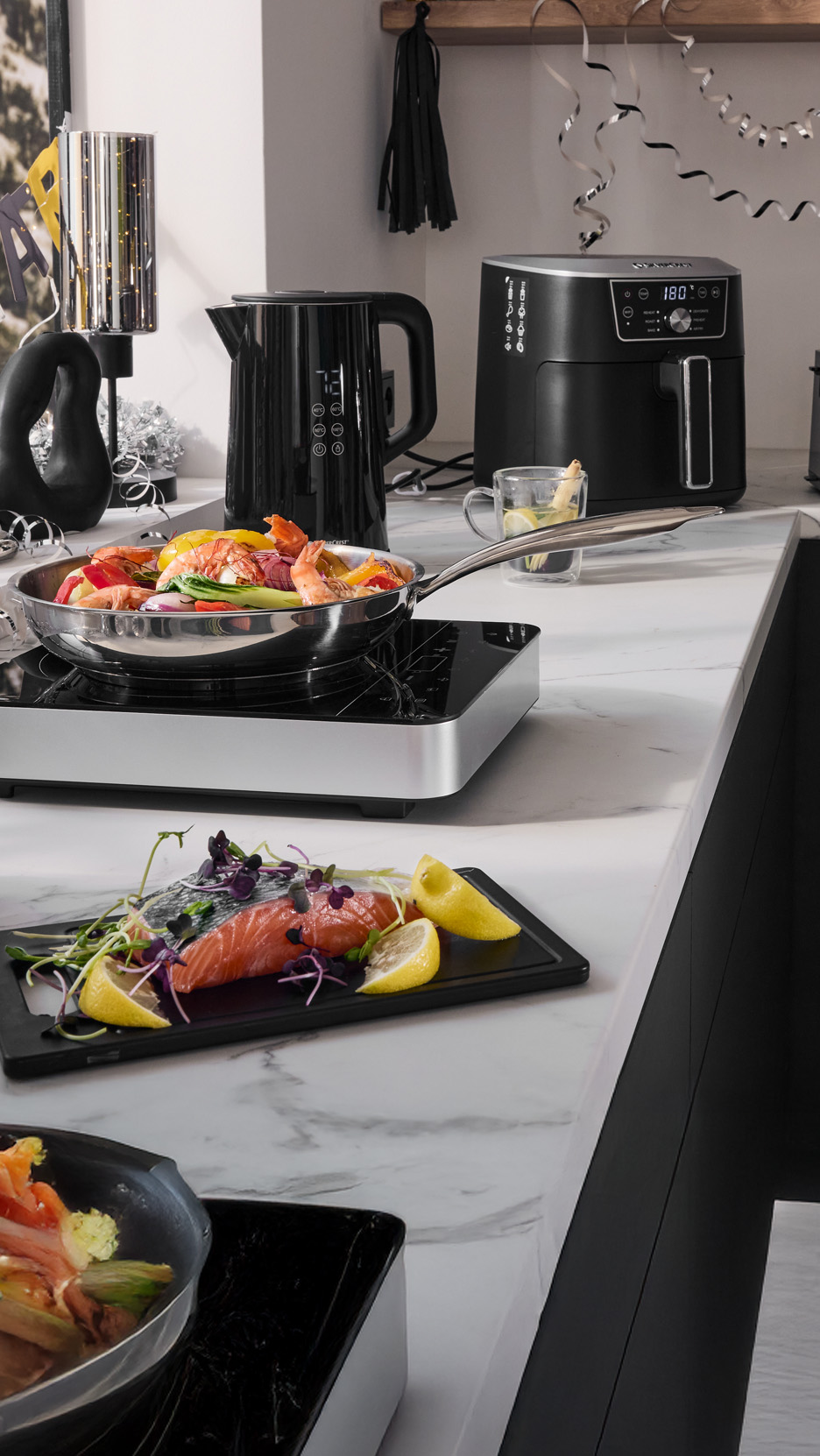 Bucătărie modernă cu fierbător, friteuză cu aer cald și plită portabilă, pregătind fructe de mare.