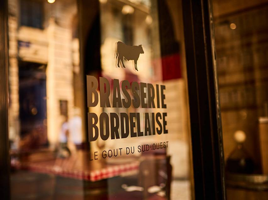Semnul Brasserie Bordelaise cu o siluetă de vacă și textul „Le Goût du Sud-Ouest”.
