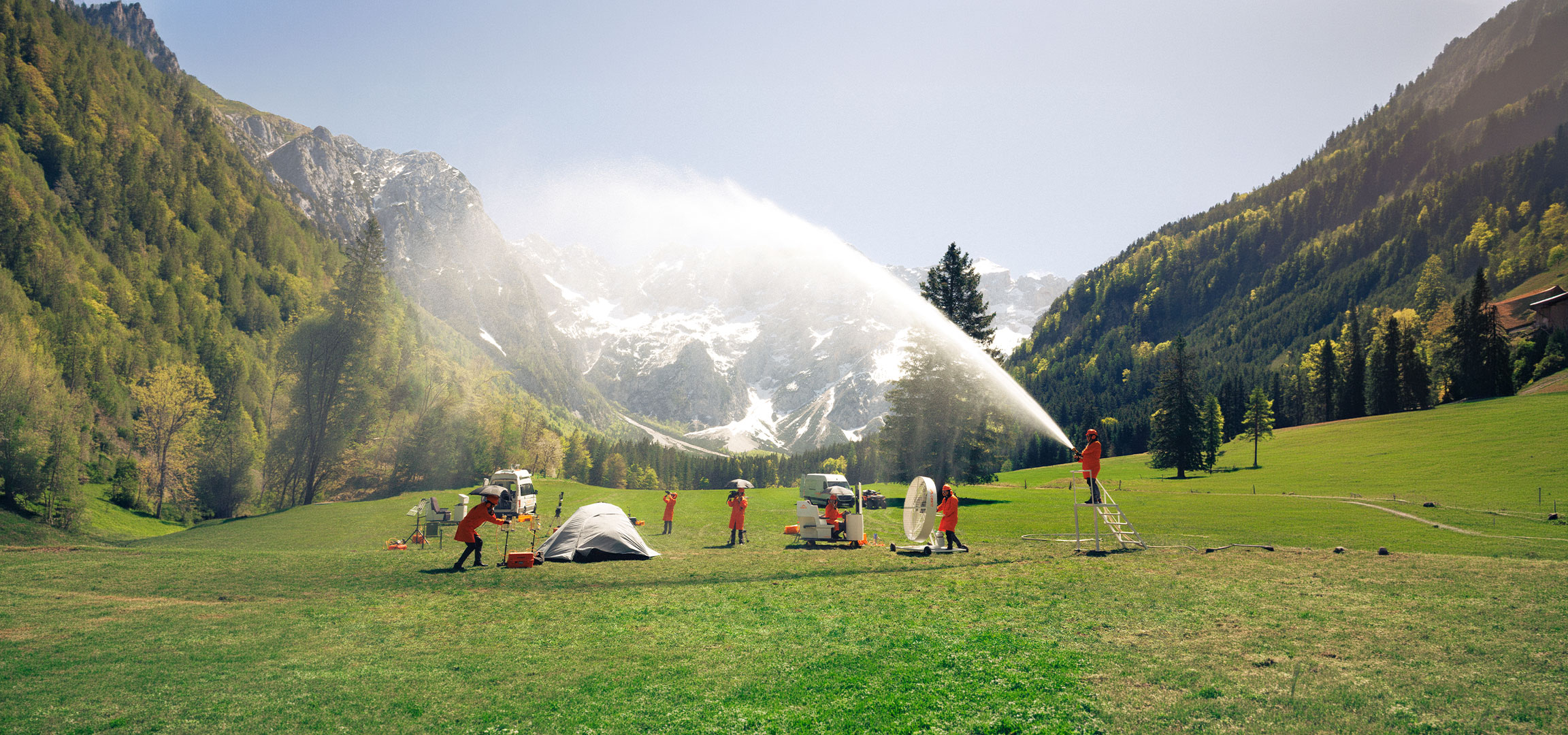 Generat de AI: Oameni în costume portocalii de protecție testând echipamente de camping și exterior într-o pajiște.