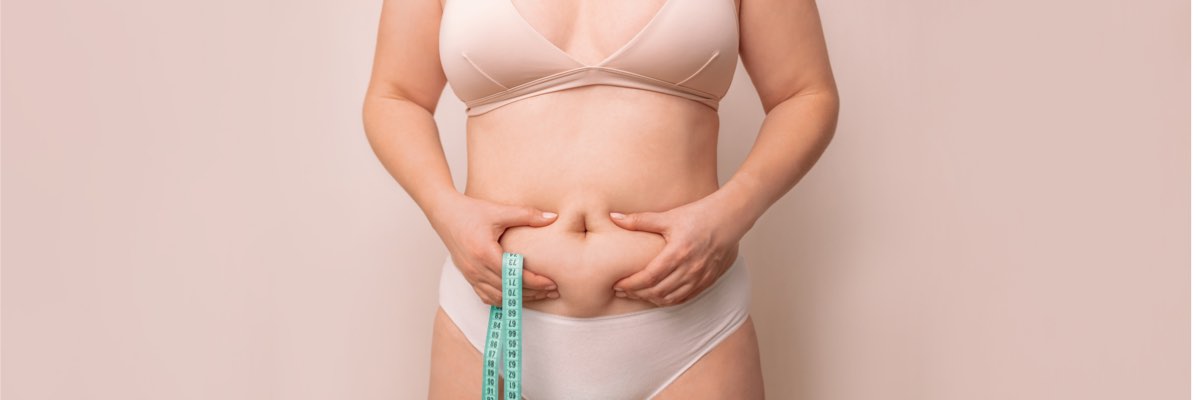 Femeie în sutien și lenjerie intimă cu bandă de măsurat, accent pe abdomen.