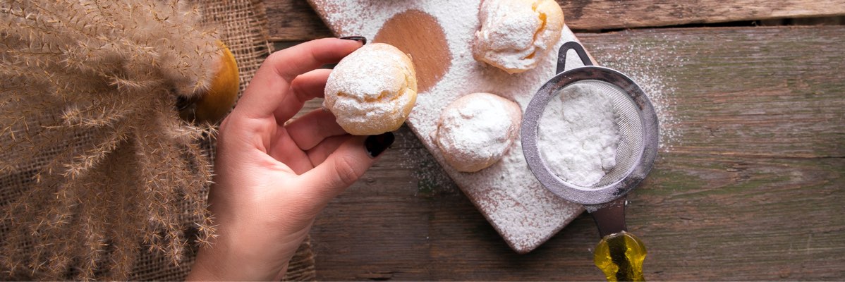 Profiterole cu zahăr pudră pe masă din lemn.