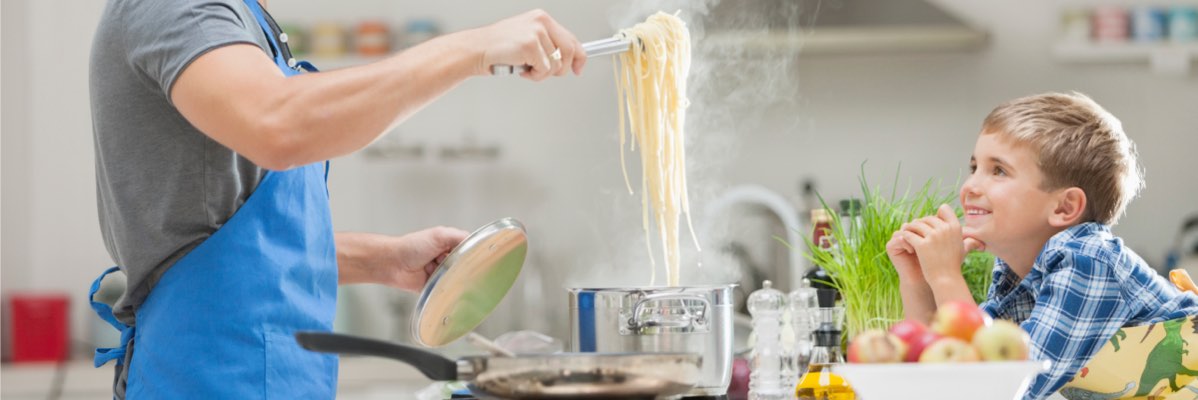 Un bărbat prepară paste în bucătărie cu fiul său.