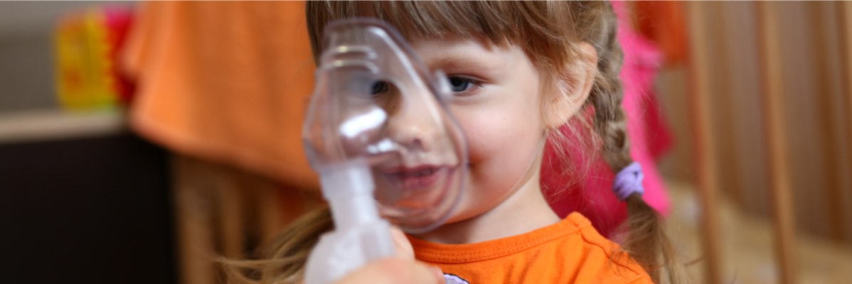 O fetiță folosește un inhalator.