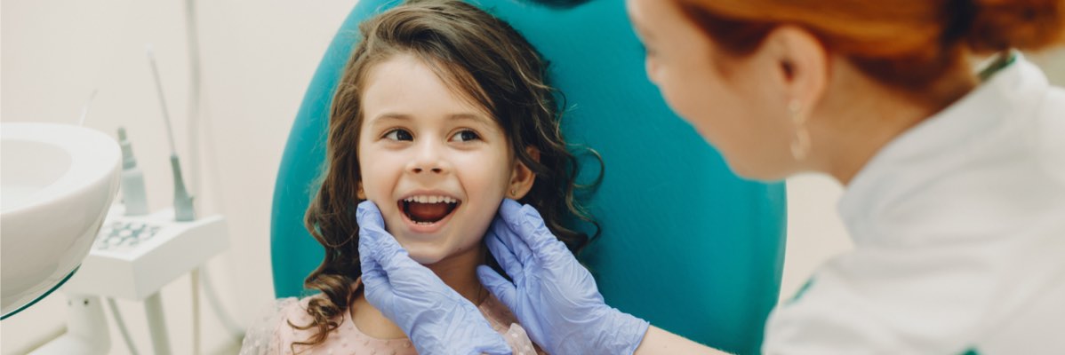 Control stomatologic pentru copii: fată zâmbitoare la dentist.