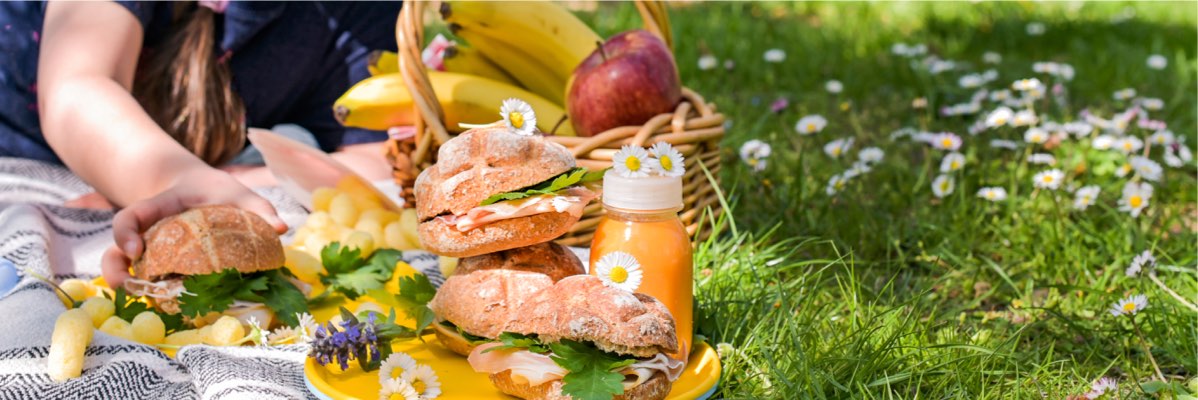 Picnic cu sandvișuri, banane și suc.