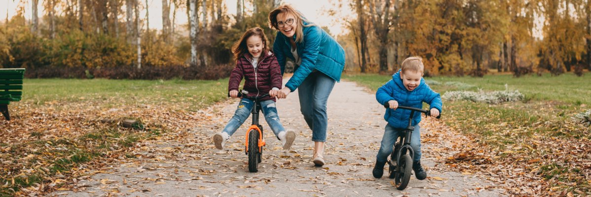 Copii pe biciclete fără pedale într-un parc de toamnă.