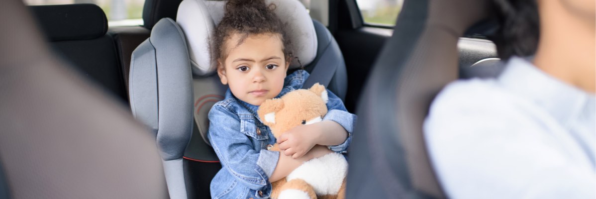 Copil în scaun auto cu ursuleț de pluș.