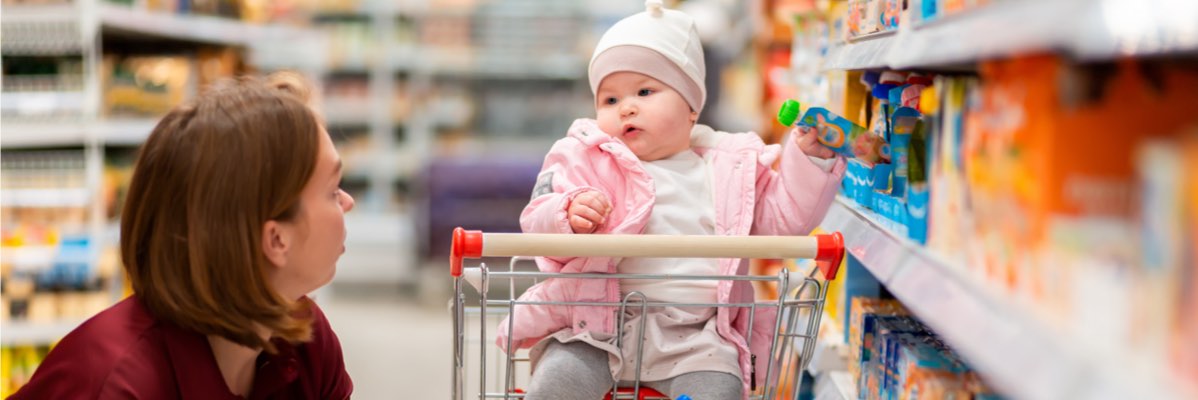 Bebeluș într-un cărucior, produse alimentare în fundal.