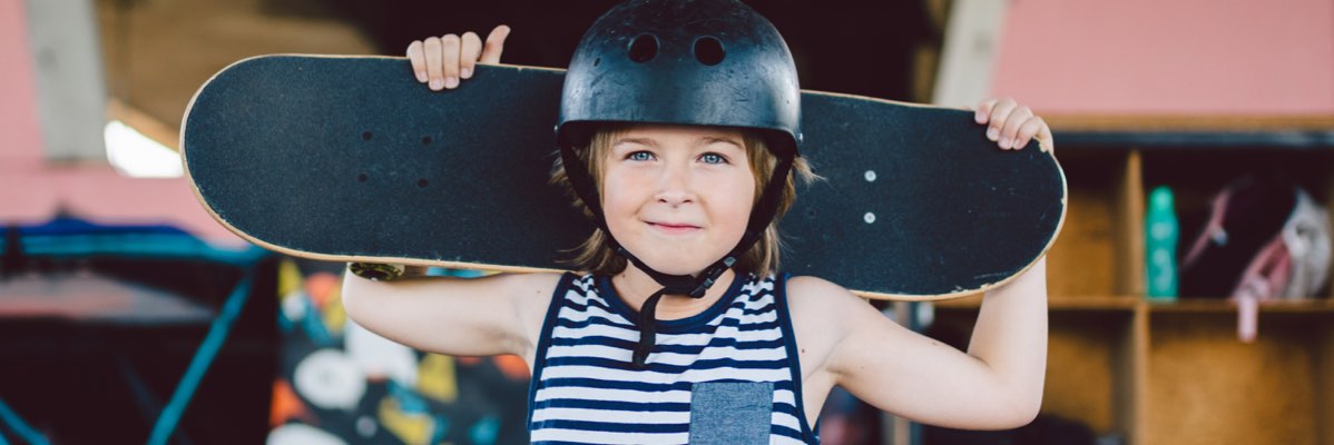 Copil cu skateboard și cască.