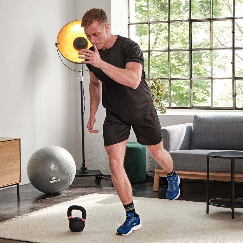 Un bărbat se antrenează cu mingea medicinală Crivit, kettlebell și mingea de gimnastică