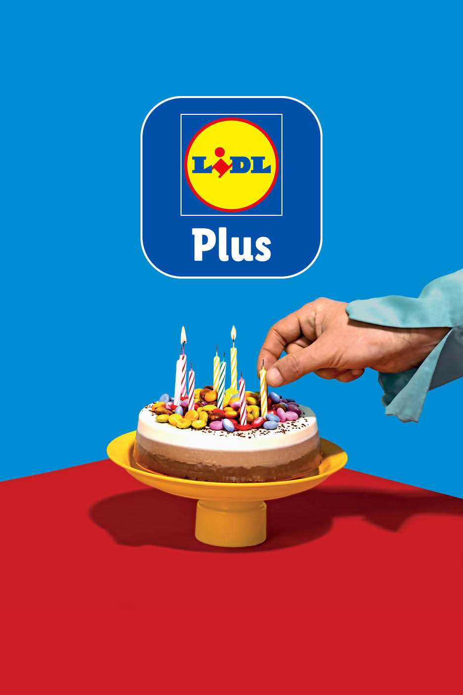 O mână aprinde lumânări pe un tort de ziua de naștere, cu logo-ul Lidl Plus deasupra.