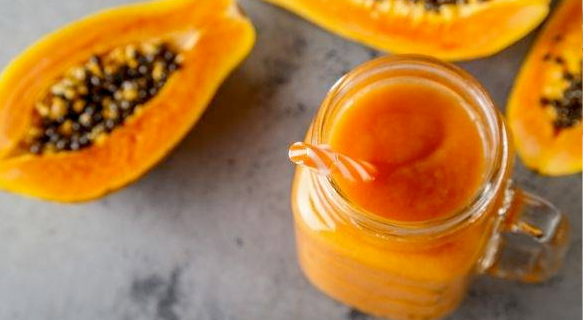 Smoothie de papaya într-un borcan și felii de papaya proaspătă.