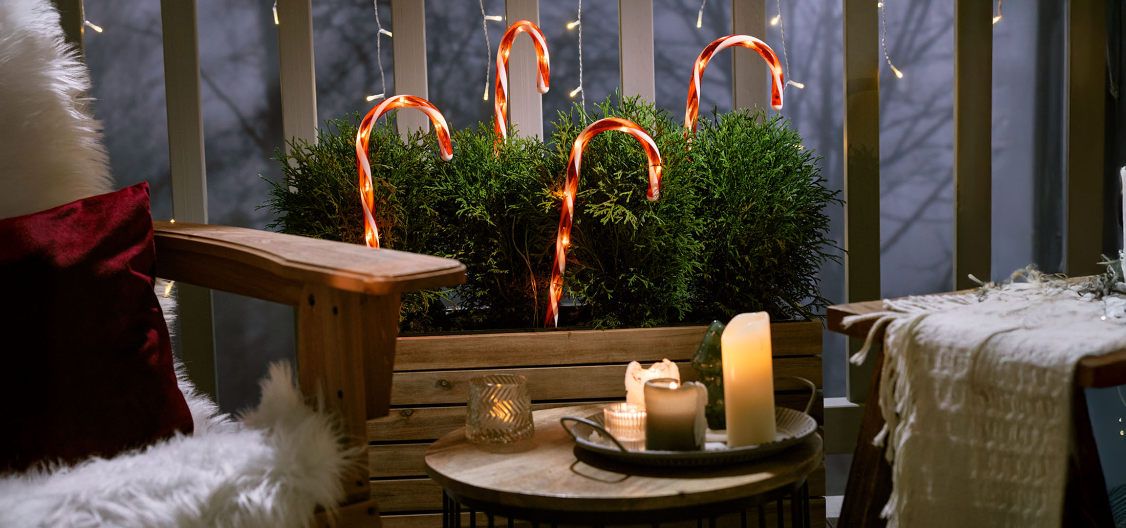 Balcon decorat de Crăciun cu un scaun, lumânări și bastoane de zahăr.