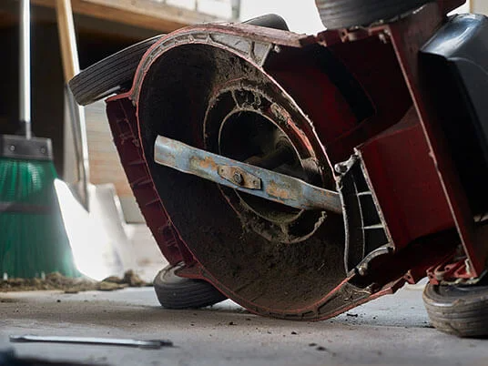 Mașină de tuns iarba murdară cu susul în jos, lamă vizibilă