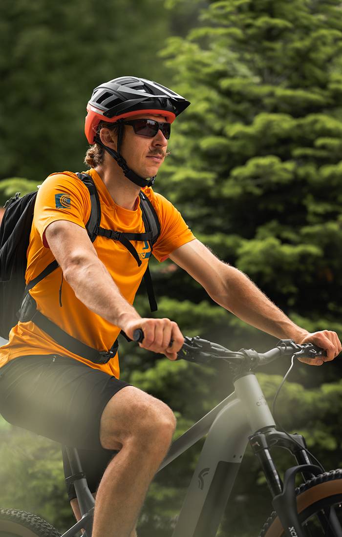 Bărbat mergând cu bicicleta de munte, purtând cască și haine de sport.