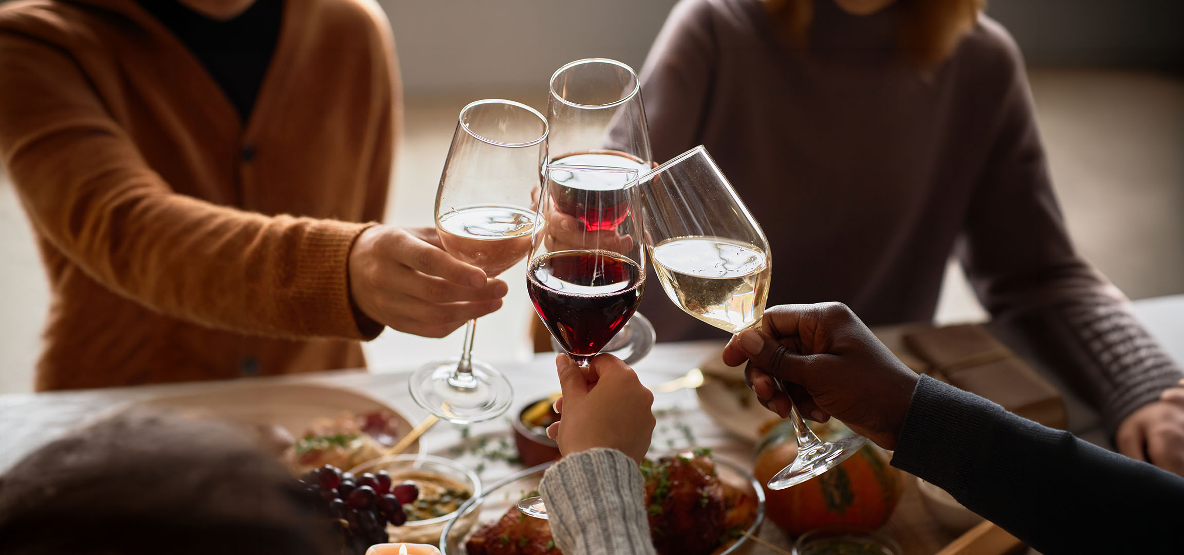 Oameni ciocnind pahare de vin roșu și alb.