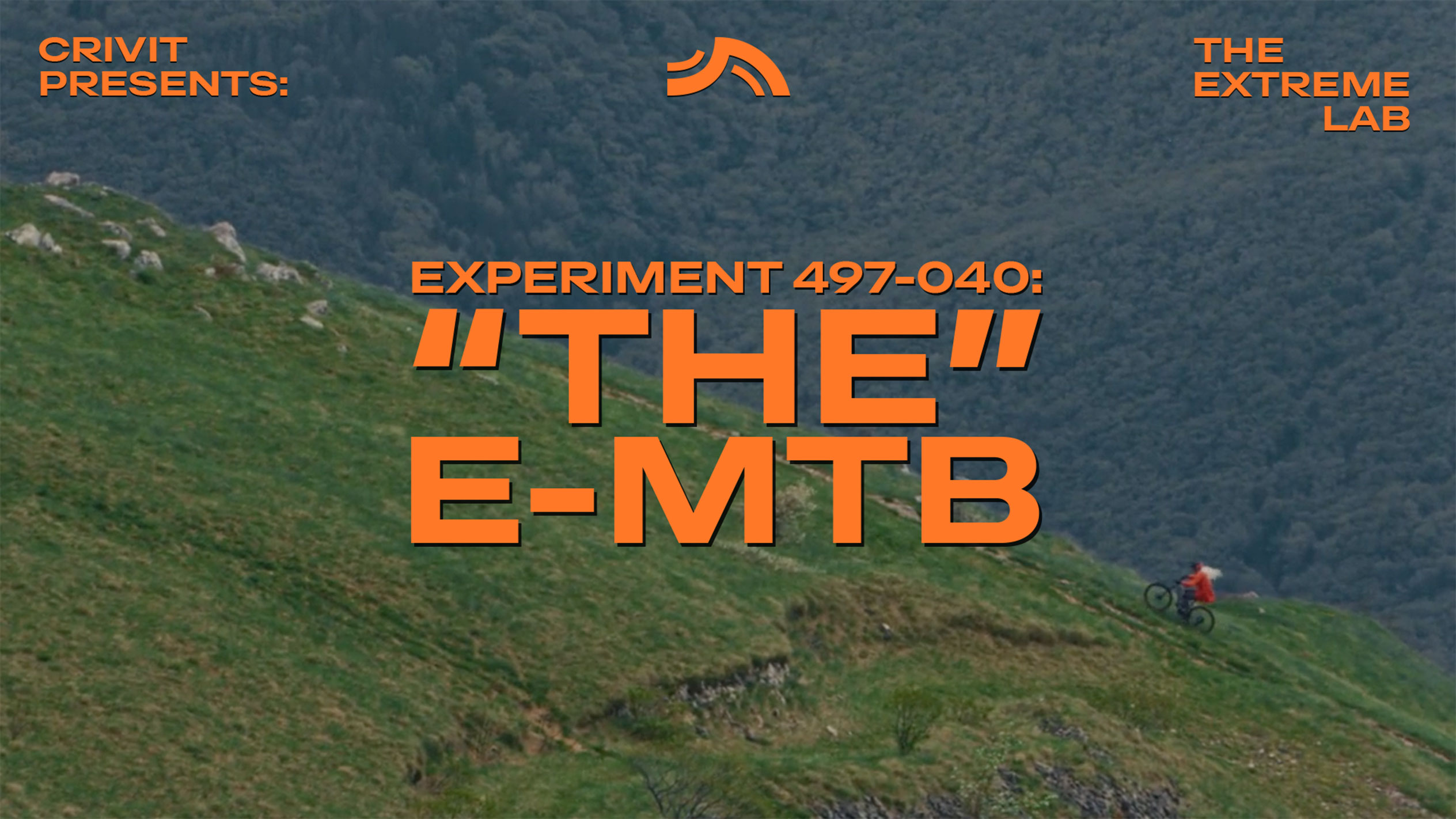 Ciclist montan pe o pantă ierboasă, cu textul 'THE E-MTB' și 'THE EXTREME LAB'.