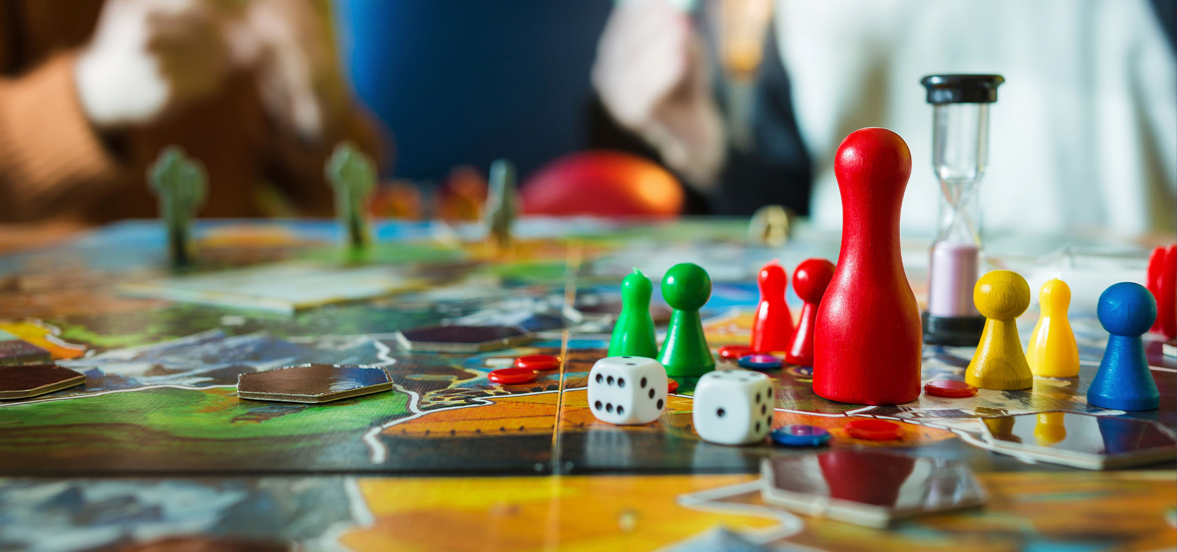 Piese colorate de joc de societate, inclusiv pioni roșii, verzi, galbeni și albaștri, cu zaruri.