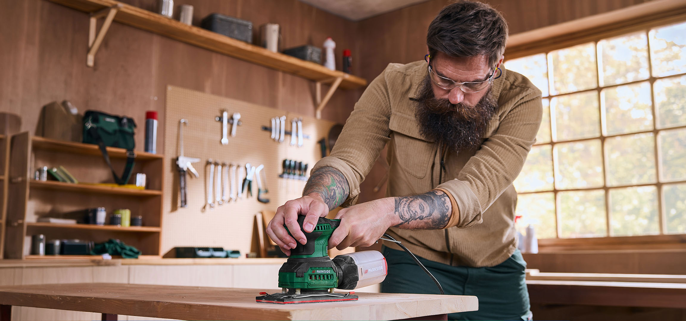 Generat de AI: Bărbat cu șlefuitor electric șlefuind o masă de lemn într-un atelier.