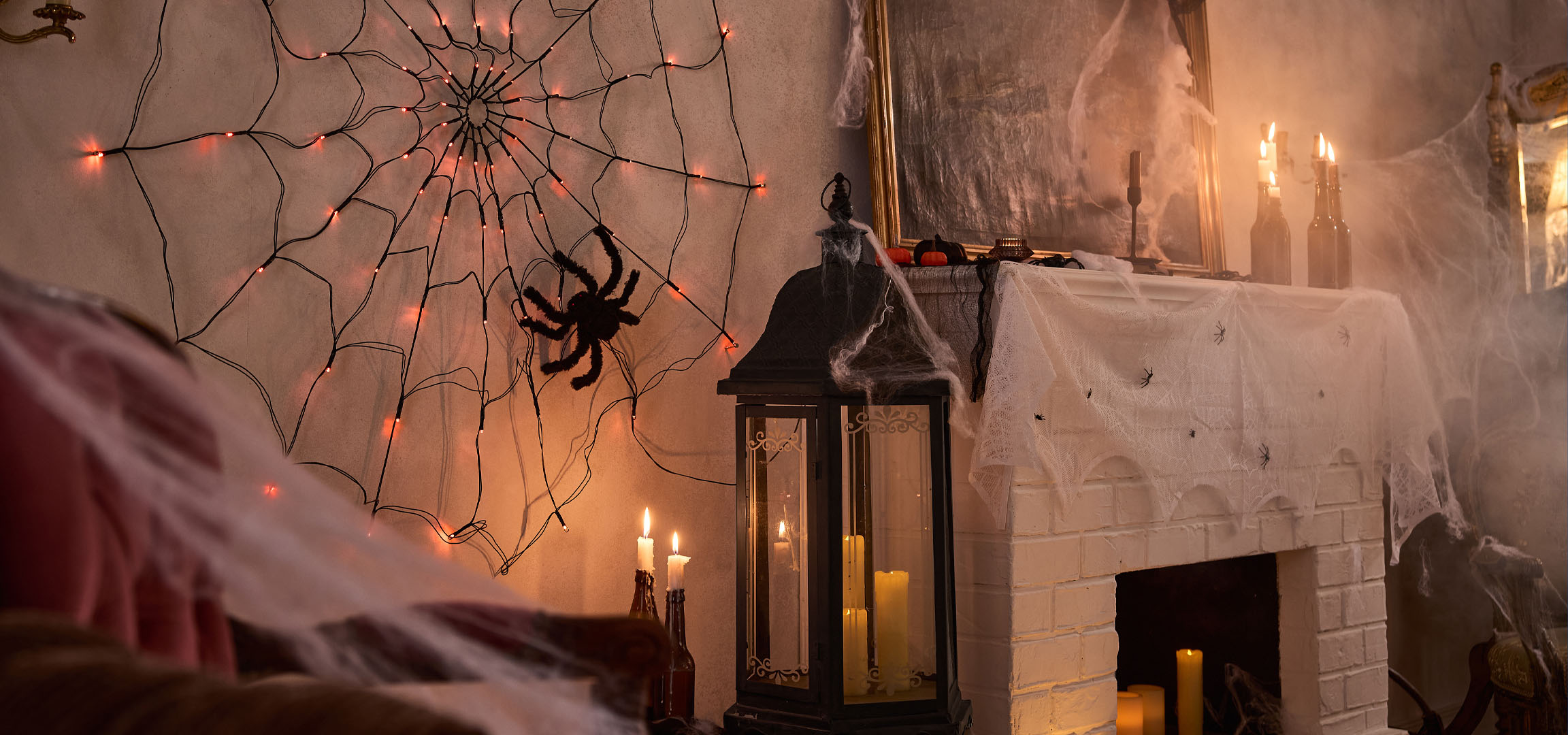 Decorațiuni de Halloween cu lumini de pânză de păianjen, un păianjen mare și lumânări.