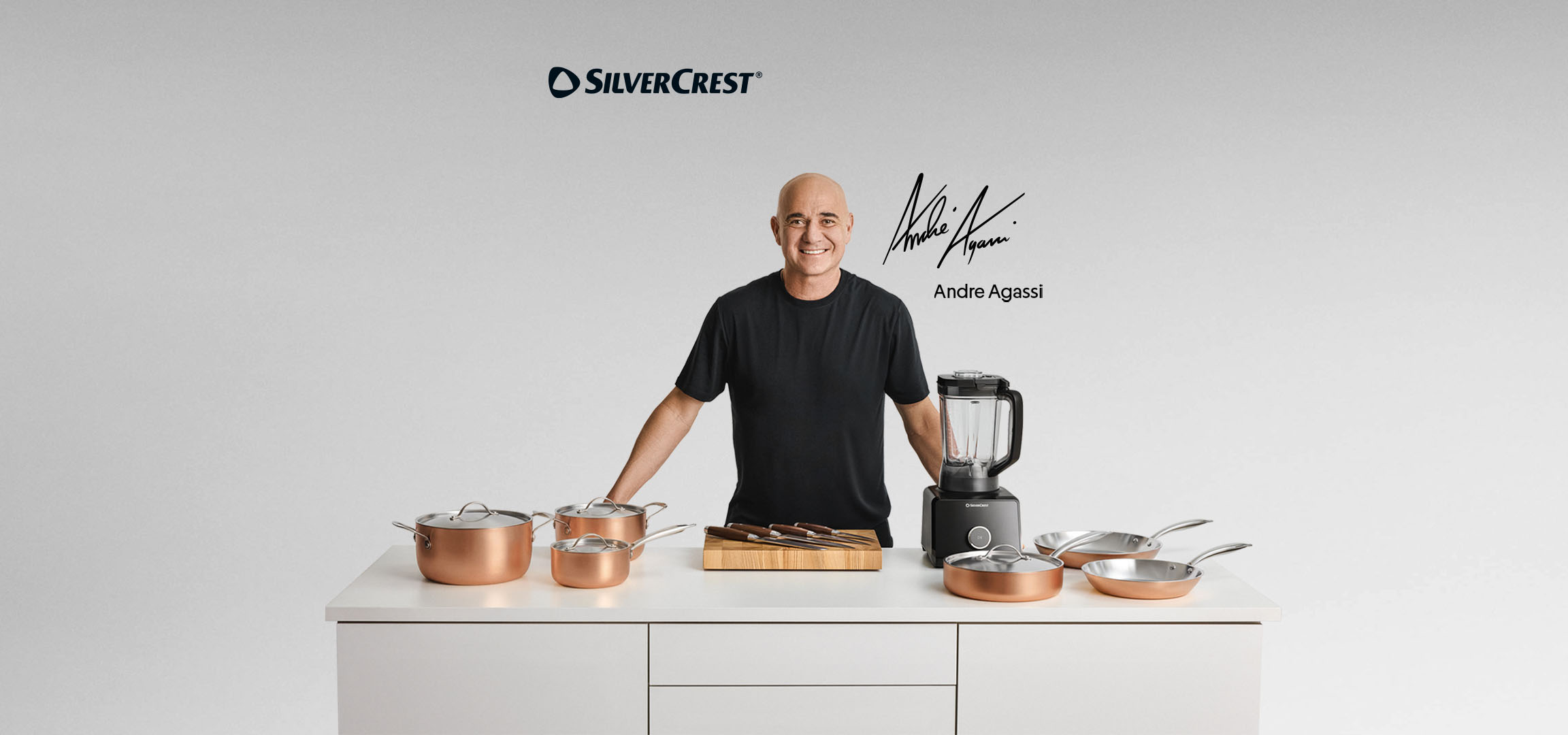 Andre Agassi cu un set de vase de gătit din cupru, un blender și un suport pentru cuțite.