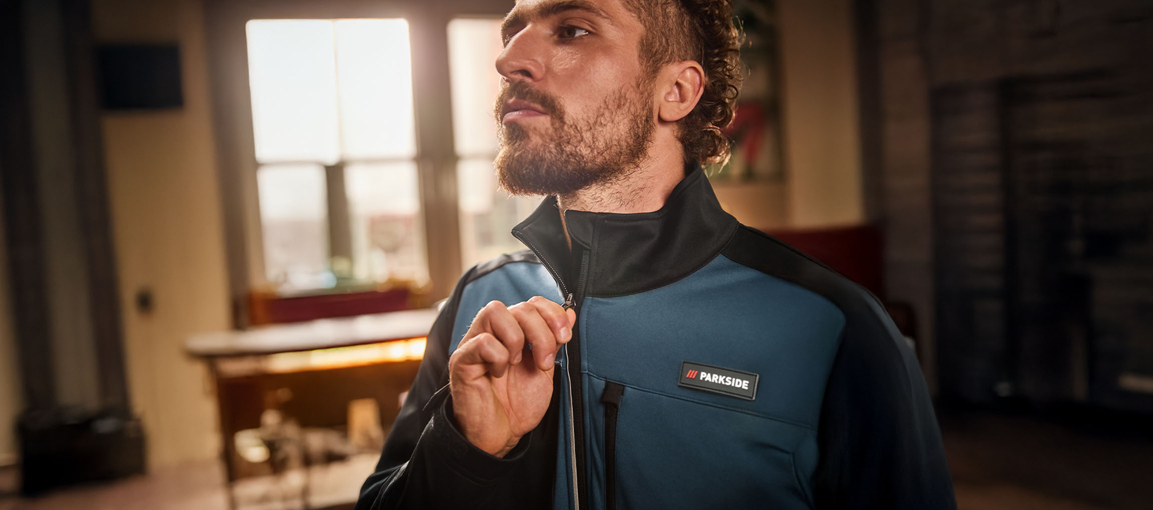 Bărbat într-o jachetă de lucru Parkside albastră și neagră, închizând-o