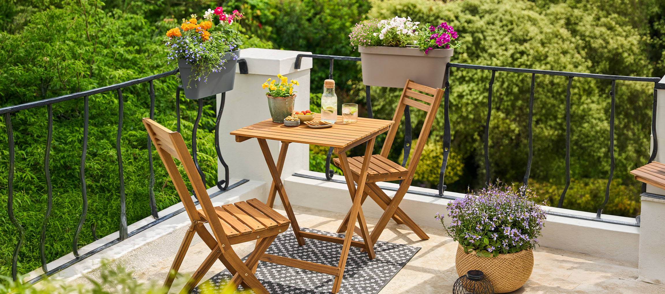 Set de mobilier de balcon cu masă și scaune pliabile, decorat cu ghivece de flori.