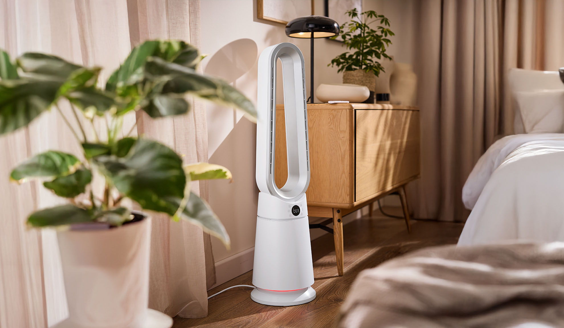 Ventilator turn alb într-un dormitor modern cu plante și mobilier din lemn.