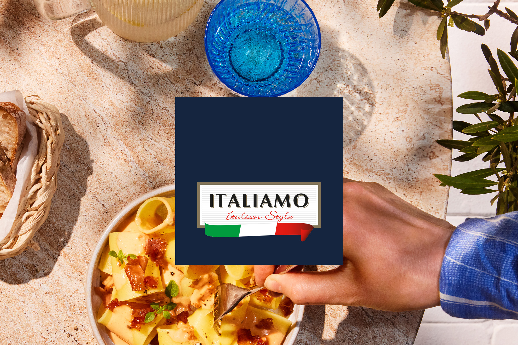 O masă italiană cu paste, pâine, băutură și o mână care ia o porție.