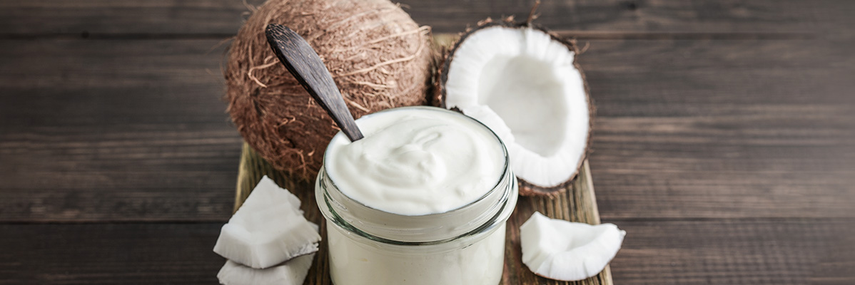 Iaurt de cocos într-un borcan, nuci de cocos și fulgi de cocos.