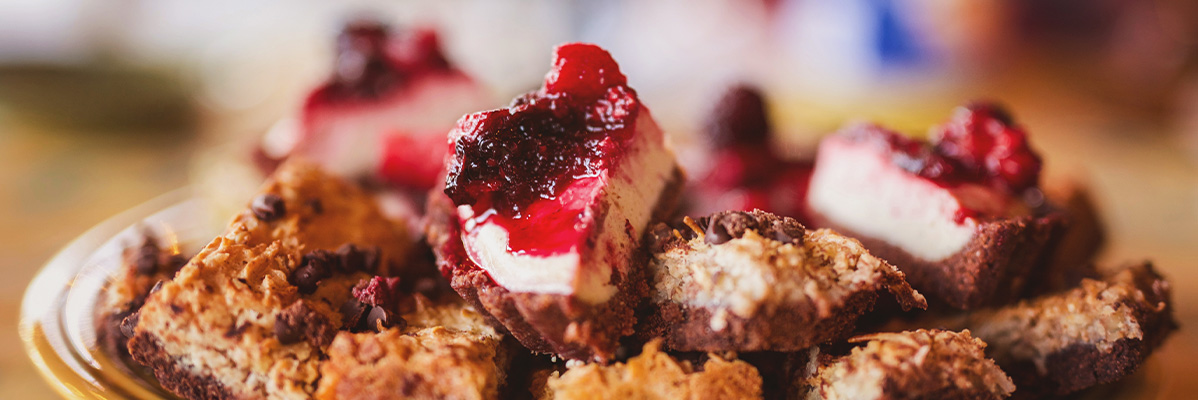 Bucăți de tort cheesecake cu compot de fructe de pădure și fursecuri cu ciocolată.