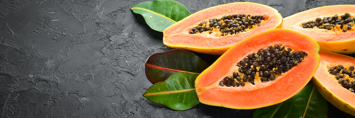 Jumătăți de papaya cu semințe pe un fundal întunecat.
