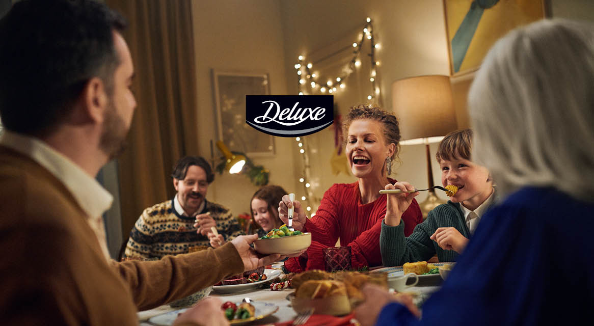 O familie se bucură de o masă festivă de Crăciun, împărtășind mâncare într-o atmosferă caldă.