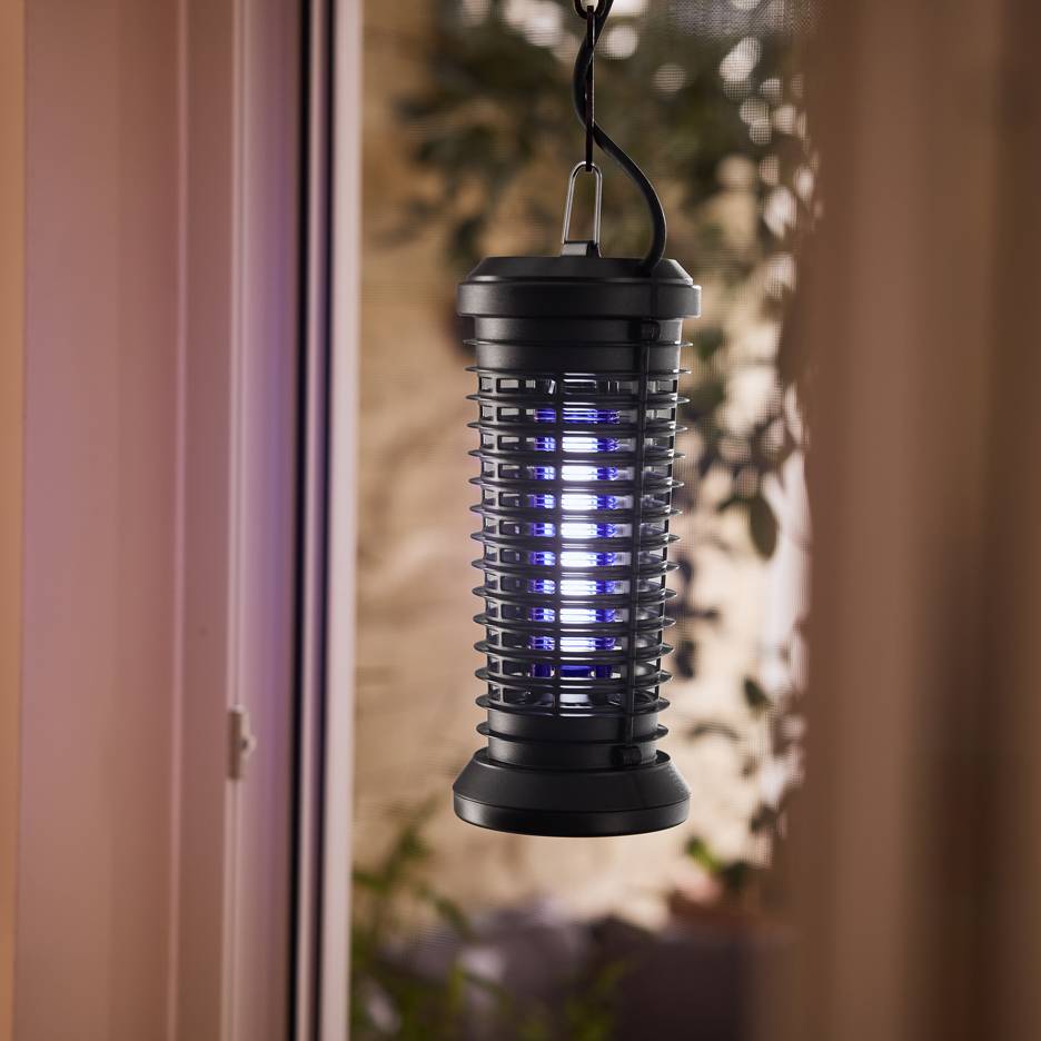 Capcană electrică pentru insecte cu lumină albastră, agățată lângă o fereastră.