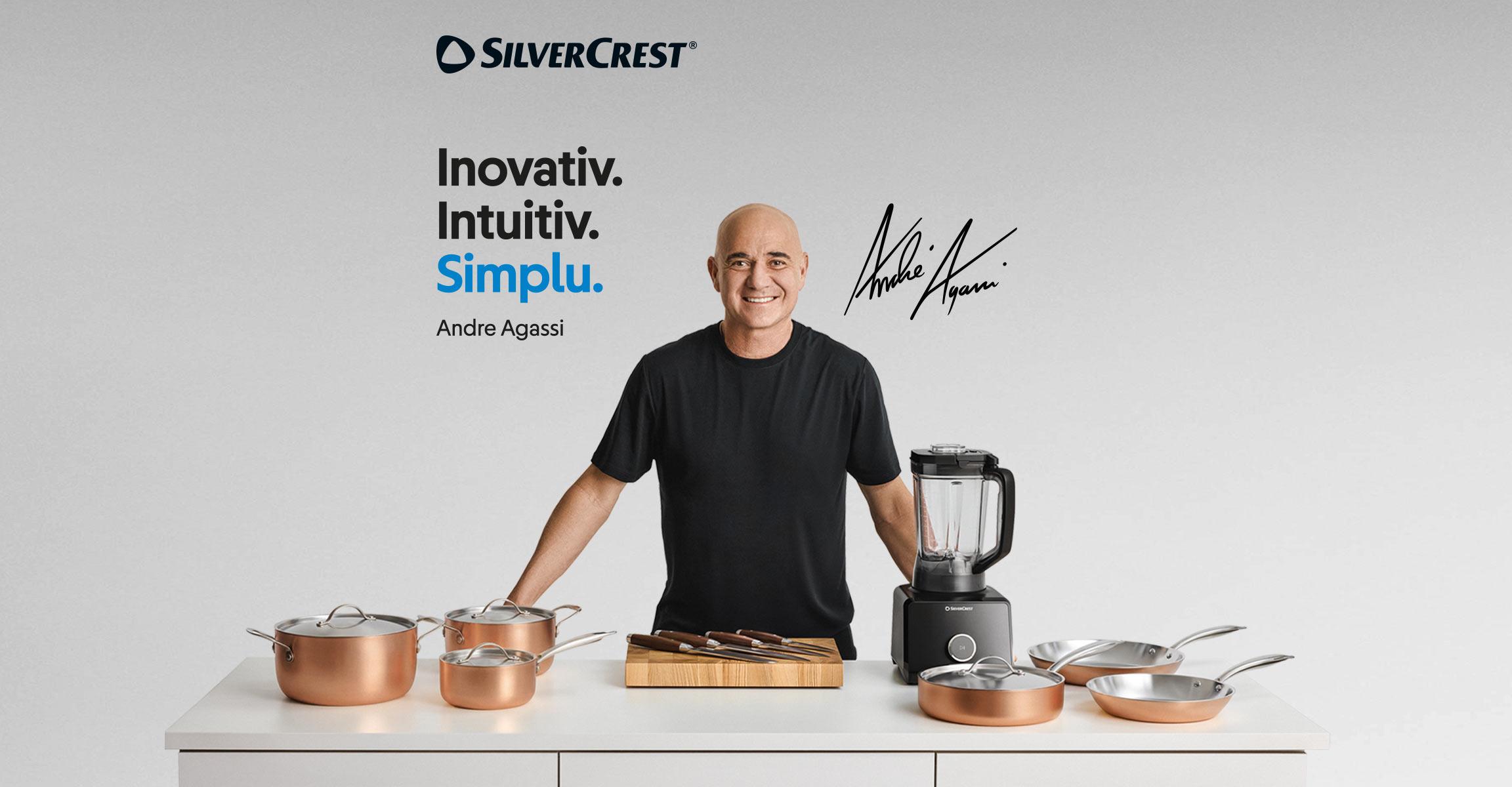 Andre Agassi prezintă o gamă de vase de gătit din cupru, cuțite și un blender pe o masă albă.